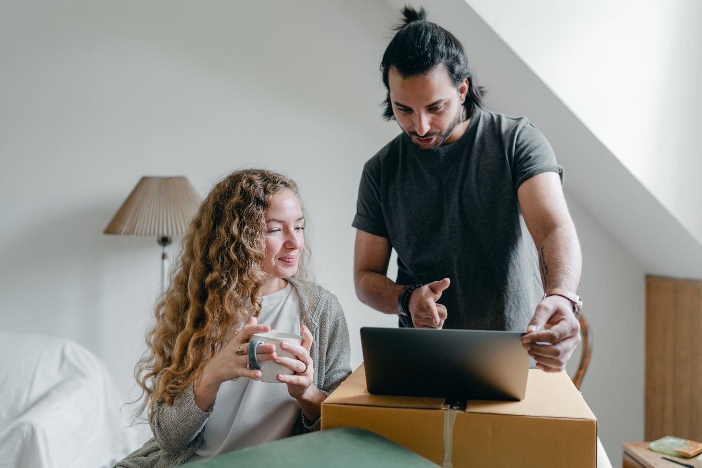 A couple comparing information on a laptop beside moving boxes
